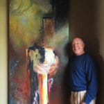 A man standing next to an abstract painting.